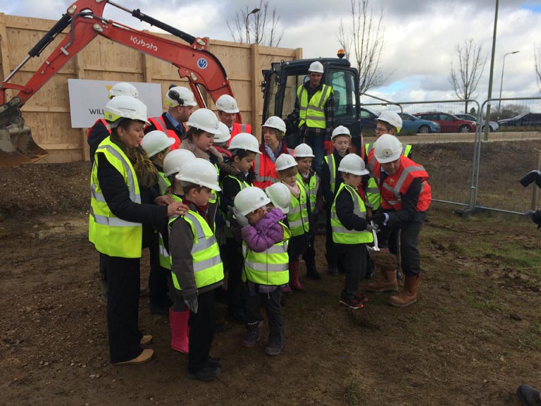 image of children in hard hats and high-vis jackets on building site